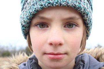 Portrait of a girl with intense green eyes wearing a cap in the winter cold