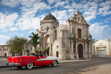 Fototapeta na wymiar Coche americano descapotable de los años 50 conduciendo cerca de la Iglesia de San Francisco de Paula en La Habana, Cuba