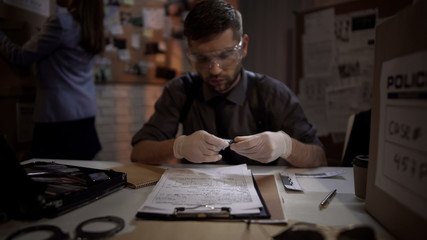 Forensic scientist male examining the evidence bullet from the crime scene