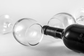  A bottle of old wine next to empty glasses. Black and white image