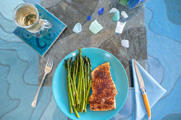 Keto lunch or dinner meal with seasoned cooked salmon, asparagus stalks and a carb-free drink