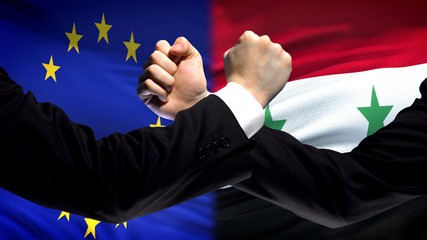 EU vs Syria confrontation, countries disagreement, fists on flag background