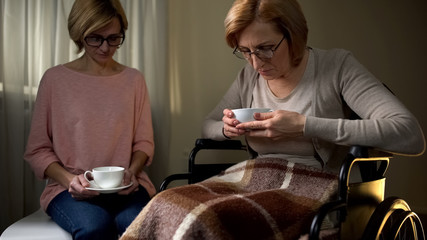 Wheelchair mother and daughter sitting together in nursing home, support visit