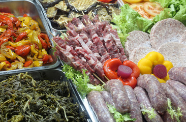 rich buffet with cooked vegetables sausages skewers and cutlets