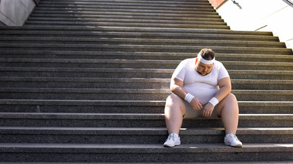 Fat man sitting on stairs after jogging, no faith in himself, insecurities - obrazy, fototapety, plakaty