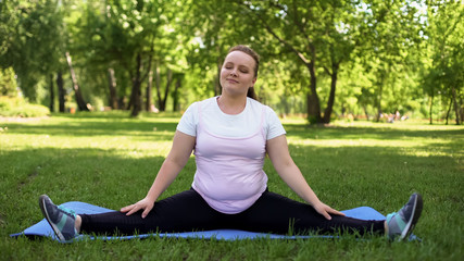 Fat woman enjoying doing yoga at park, fitness motivation, active lifestyle