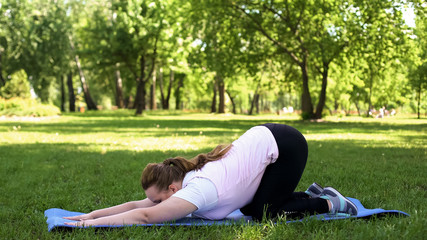 Fat woman stretching after exercising at park, active healthy lifestyle, nature