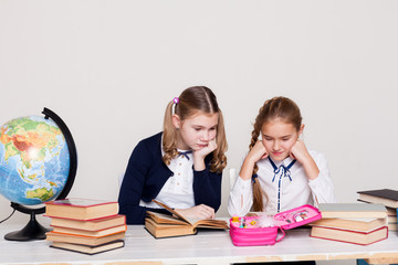 two girls schoolgirls sitting at his desk on the lesson at school