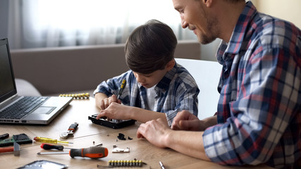 Father and son repairing small household appliances, support and reliance