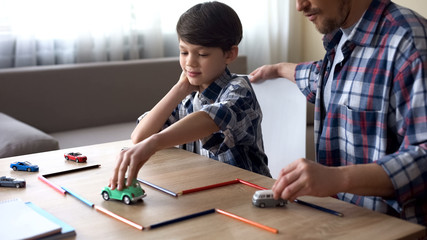 Kind father playing toy cars with his little son, parental care, togetherness