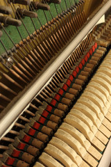 Obraz premium A close view of the mechanic of an upright piano, with tuning hitch pins, hammer heads, the vibrating strings and the soft mute (sordino) felt cloth