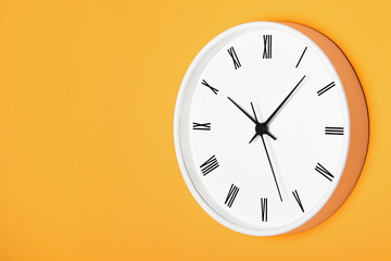 White round clock with black numbers isolated on orange wall. Time perspective empty copy space background.