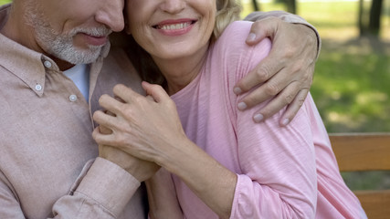 Fototapeta premium Loving senior couple embracing in park, comfortable retirement, secure old age