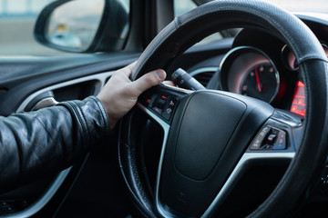 Male driver holding steering wheel while driving