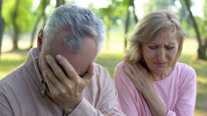 Mature couple crying sitting outdoors, incurable disease, retirement problem