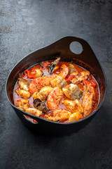 Traditional French Corsican fish stew with prawns, mussels and fish as top view in a modern design...