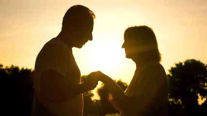 Fototapeta na wymiar Attentive husband holding wife hand, romantic date at sunset in park, care