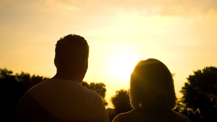 Silhouette of senior couple watching sunset together, secure old age, well-being