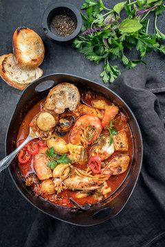 Traditional French Corsican fish stew with prawns, mussels and fish as top view in a modern design Japanese cast-iron roasting dish