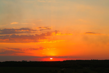 Obraz premium Natural sunset over the dark field or forest. Bright dramatic sky and dark ground in the evening at sunset.