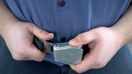Obese male passenger fastening seat belt while sitting on airplane, safe flight