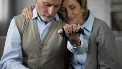 Happy husband and wife on pension sitting on couch, senior couple hugging