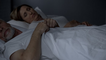 Elderly couple sleeping in bed, lack of emotions problems with potency menopause