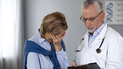 Doctor showing unhappy woman bad test results, cancer treatment, oncology