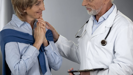 Experienced doctor informing lady about positive treatment results, good news