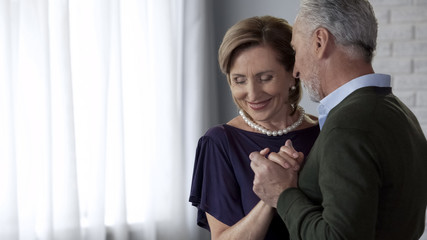 Happy senior couple dancing, both smiling, celebrating wedding anniversary