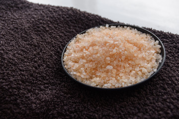Sea salt in small black container on brown towel