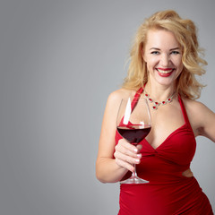 Attractive middle age woman in red evening dress with glass of red wine.