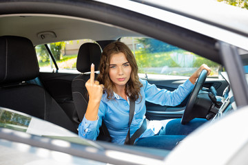 Young woman making obscene gestures while driving on the road