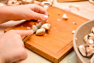 Cooking at home. The child cuts champignons. Children's hands with a knife close-up - cuts mushrooms.