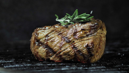 A large piece of meat of beef or pork cooked charcoal barbecue close-up . Sprig razmarina top