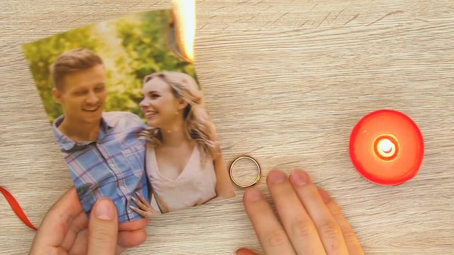 Woman burning family photo and holding engagement ring, divorce and betrayal