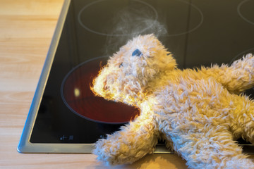 Teddy Bär fängt auf einer heißen Herdplatte Feuer