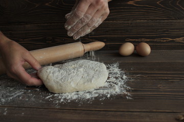 Тесто на деревянной доске посыпанное мукой .