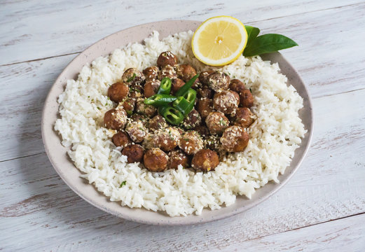 Juicy diet meatballs with rice on a wooden table. Close up. 