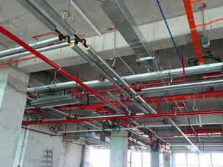 Air condition duct and other services above ceiling level coordinated and installed by construction workers  at the construction site  - obrazy, fototapety, plakaty
