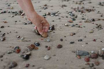 Senior woman hand picking up stone at beach