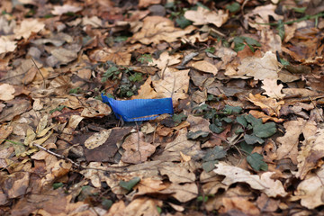 Fototapeta na wymiar Plastic cup broken blue ground leaves pollution litter waste