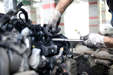 Mechanic hand checking and fixing a broken car in car service garage