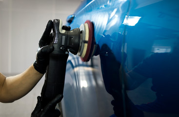Spray Painter works at a car with a polisher