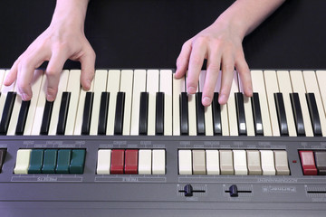 A right hand playing a B (SI) major chord on an old black piano with yellowed cracked keys, pressing the B (SI), D# sharp (RE#), F# sharp (FA#) notes