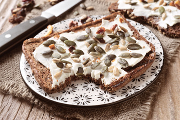 slice of whole wheat bread spread with cheese and sunflower seed cover
