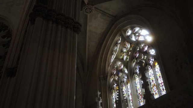 Beautiful dark cappela with colored stained glass window. Panning shot sun shining through window and lens catch the flare. Cathedral Portugal