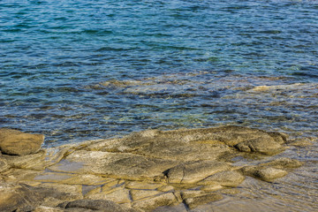 Mediterranean sea local scenic rocky coast shoreline with stone from under water and vivid blue ripple surface