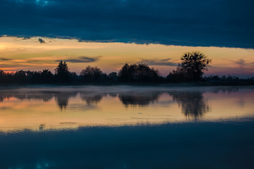 Reflection of clouds in a calm lake after sunset