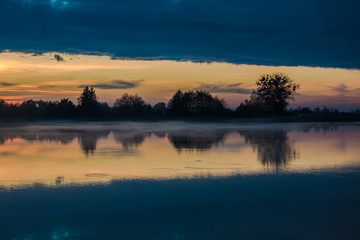 Reflection of clouds in a calm lake after sunset